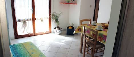 A dining area with a table set for two, a bench, and a potted plant.