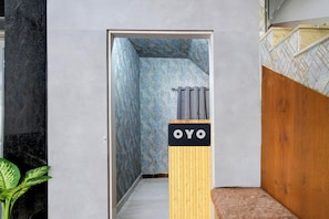 Un pasillo con un papel tapiz estampado, una partición de madera con la señalización 'OYO' y una planta.