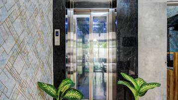 Un ascensor con pantalla digital, puertas de vidrio y un revestimiento de pared con diseño.