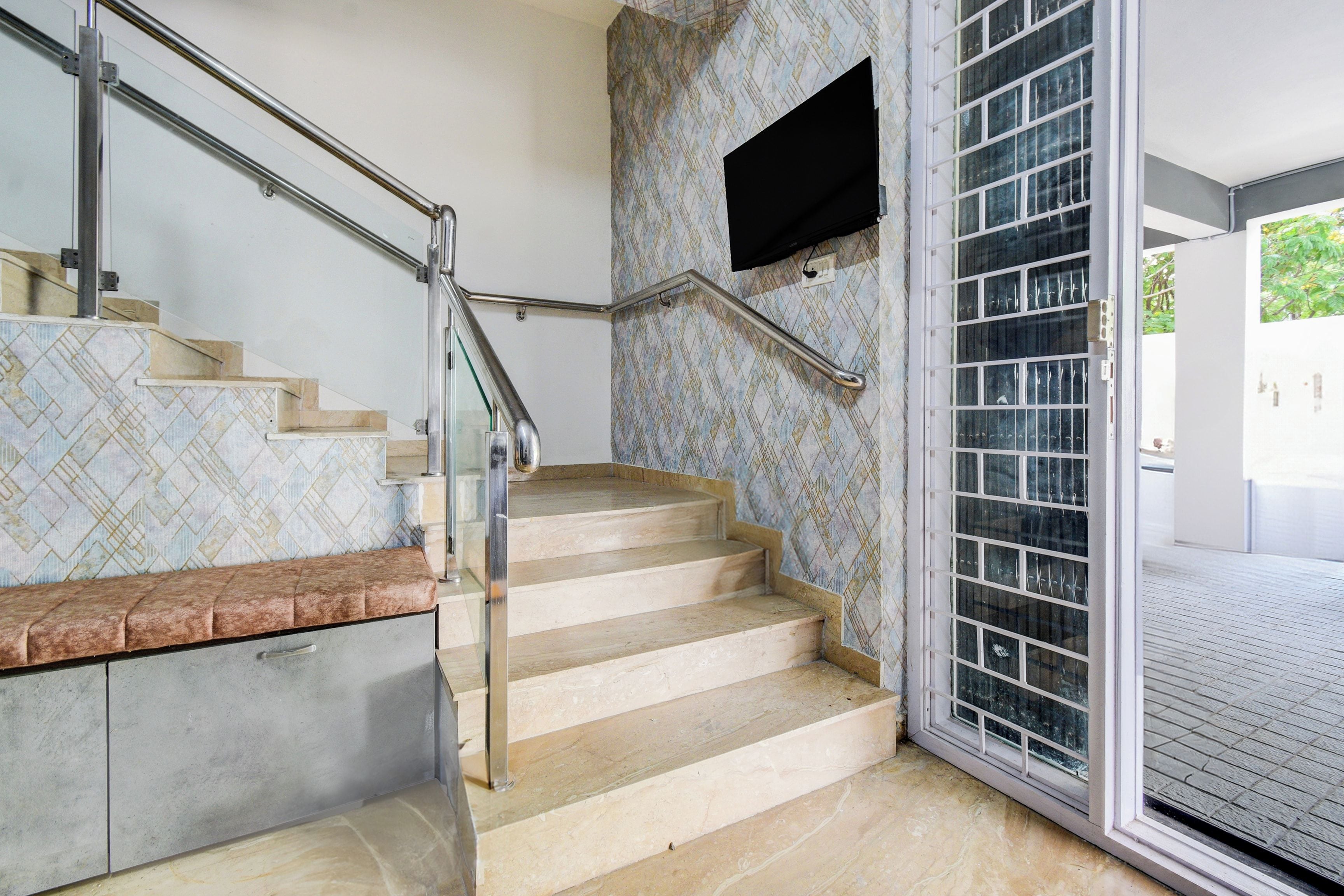 Una escalera con barandilla, un banco y un revestimiento de pared decorativo.