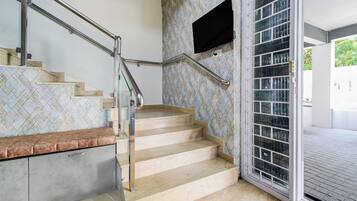 Una escalera con barandilla, un banco y un revestimiento de pared decorativo.