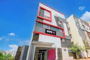 Un hotel de varios pisos con un diseño moderno, que destaca por una llamativa combinación de colores rojo y blanco, y un letrero que indica que es un hotel OYO.