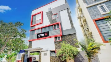 Un hotel moderno con un llamativo letrero de OYO, fachada de piedra y entrada con portón.
