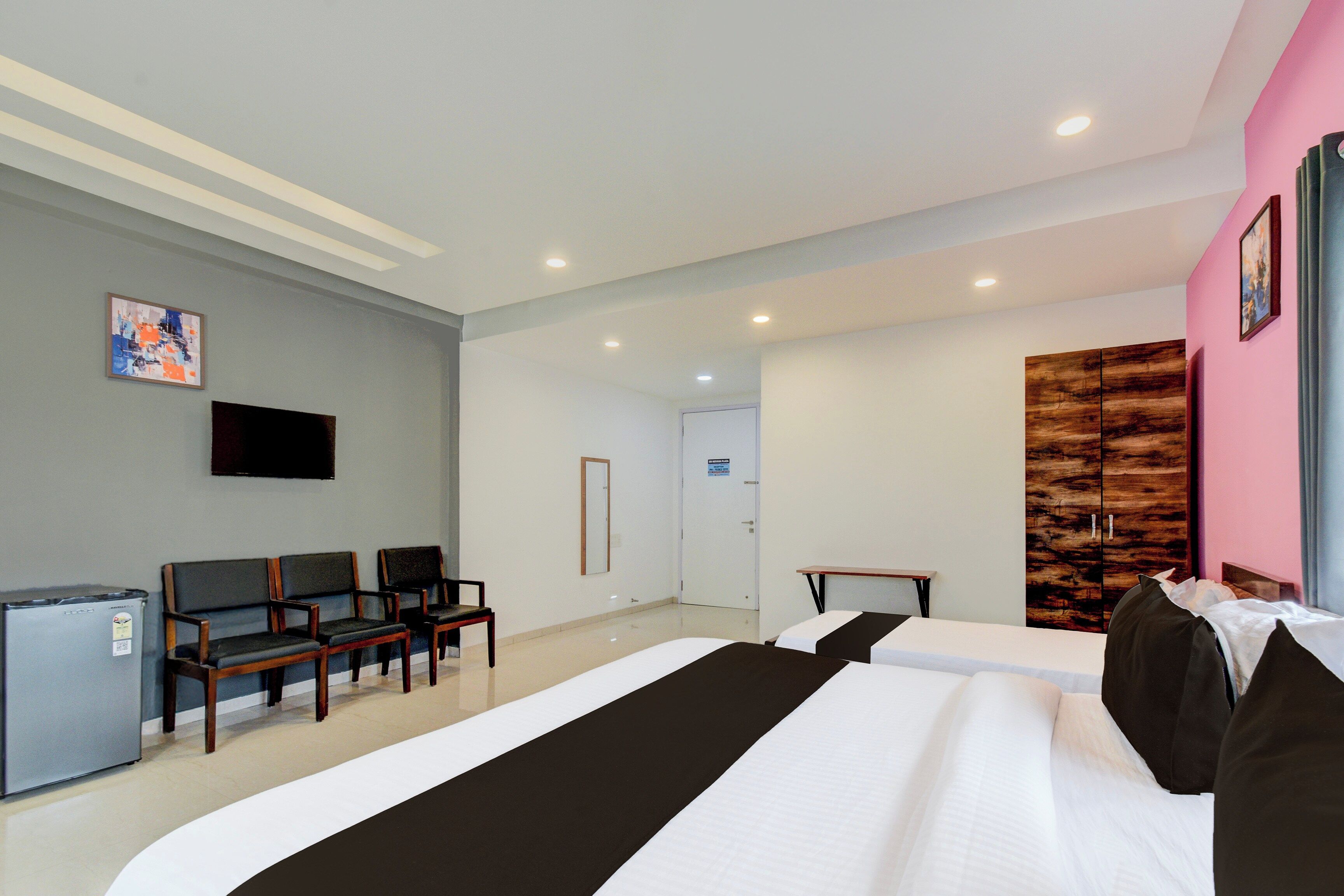 Quarto de hotel com uma cama grande, uma escrivaninha, uma cadeira, uma televisão e um guarda-roupa.