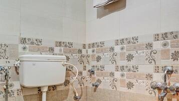Un baño con inodoro, ducha y un perchero para toallas.