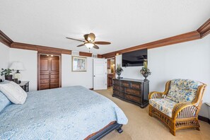 A bedroom with a bed, dresser, chair, ceiling fan, and a door. - #801 Blue Surf  Luxury 3/3 Oceanfront Condo Traffic Free Beach (Daytona Beach Shores)
