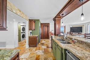A spacious kitchen with granite countertops, wooden cabinets, and a built-in dishwasher. - #801 Blue Surf  Luxury 3/3 Oceanfront Condo Traffic Free Beach (Daytona Beach Shores)
