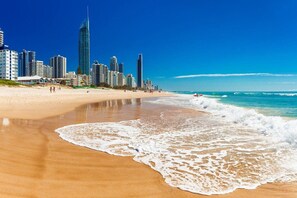 A beach with a city skyline in the background, featuring high-rise buildings. - Luxury Chevron Island Retreat | Water & City Views (Surfers Paradise)