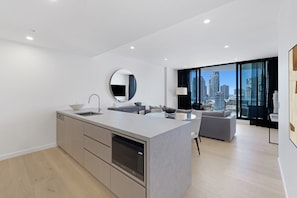 A modern kitchen with a built-in microwave, a sink, and a large island. - Luxury Chevron Island Retreat | Water & City Views (Surfers Paradise)