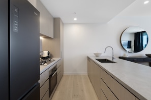 A modern kitchen with a built-in refrigerator, stove, and oven. - Luxury Chevron Island Retreat | Water & City Views (Surfers Paradise)