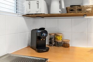 A kitchen with a coffee maker, jars, and a toaster on the counter. - Bright 2-Bed Apartment Near Cairns Esplanade (Cairns North)