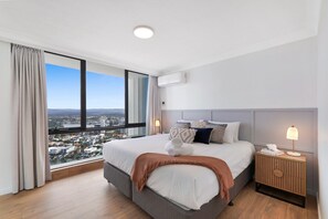 A modern hotel room with a large bed, a nightstand, and a view of a cityscape. - High-Rise 2-Bed Apartment in Surfers Paradise (Surfers Paradise)