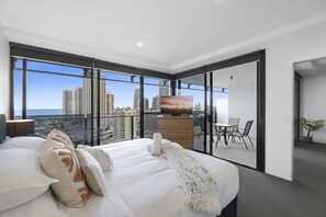 A modern hotel room with a large bed, a flat-screen TV, a balcony with a city view, and a dining area. - Ocean View | Circle on Cavill 2BR Apartment (Surfers Paradise)
