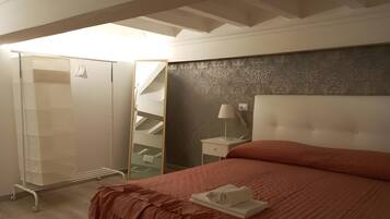 Une chambre à coucher comprenant un lit, une table de chevet, un miroir, une armoire et un escalier.