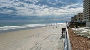 A beach with a walkway, a fence, and a building in the background. - #806 Ashley 2/2 Oceanfront Condo Daytona Beach Shores (Daytona Beach Shores)