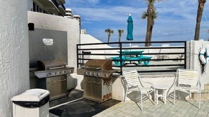 Eine Außenpatio mit Grill, Stühlen und Tisch.
