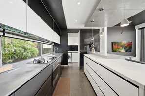 A modern kitchen with a large island, built-in appliances, and a view of greenery outside. - 4-Bed Retreat With Cinema in Wright (Wright)