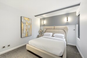 A modern bedroom with a bed, a nightstand, a lamp, and a wall-mounted artwork. - 4-Bed Retreat With Cinema in Wright (Wright)