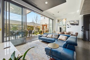 A modern living room with a blue sofa, a dining area, and a kitchen with a large refrigerator. - 4-Bed Retreat With Cinema in Wright (Wright)
