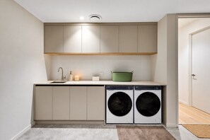 A compact kitchen with a sink, a green pot, and two front-loading washing machines. - Spacious 3-Bed Townhouse In Mile End (Mile End)