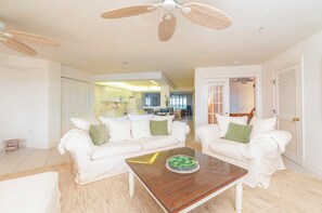A living room with a white sofa set, a coffee table with a decorative bowl, and a ceiling fan. - 8505 Towers in Ponce Inlet, FL (Ponce Inlet)