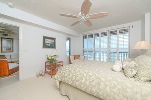 A bedroom with a large bed, a ceiling fan, a window with blinds, and a view of the outdoors. - 8505 Towers in Ponce Inlet, FL (Ponce Inlet)