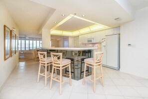 A modern kitchen with a central island, bar stools, and a refrigerator. - 8505 Towers in Ponce Inlet, FL (Ponce Inlet)