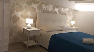 Una camera da letto con un letto, due comodini con lampade, un tavolino da notte e carta da parati floreale.