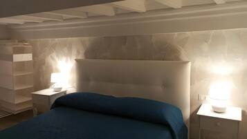 Une chambre avec un grand lit, deux tables de chevet et un mur orné d’un motif de feuilles.