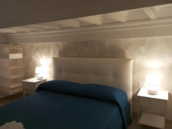 Ein Schlafzimmer mit einem großen Bett, zwei Nachttischen und einer Wand mit einem Blattmuster.