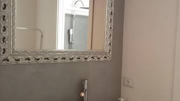 Une salle de bain avec un lavabo blanc, un miroir doté d’un cadre orné et un meuble-lavabo en bois.