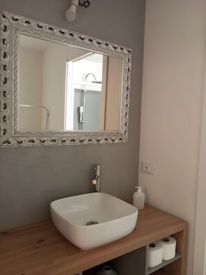 Ein Badezimmer mit einem weißen Waschbecken, einem Spiegel mit aufwendigem Rahmen und einer Holzeinrichtung.