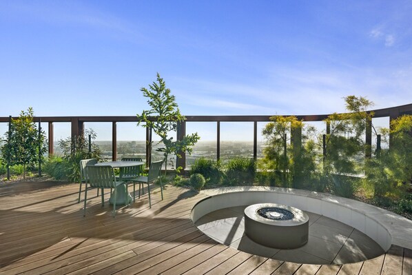 A wooden deck with a circular seating area and a table with chairs. - High-Rise 2-Bed Apartment Near Southbank (South Melbourne)