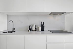 A modern kitchen with a double sink, a kettle, a toaster, and a knife block. - High-Rise 2-Bed Apartment Near Southbank (South Melbourne)