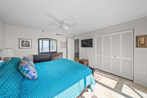 A bedroom with a bed, a ceiling fan, a dresser, a wardrobe, and a television on the wall. - 8D Royal Atlantic 2/2 ocean view unit. (Daytona Beach Shores)