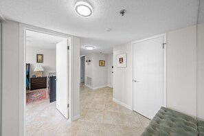 A hallway with a tiled floor, white walls, and a door leading to another room. - 8D Royal Atlantic 2/2 ocean view unit. (Daytona Beach Shores)