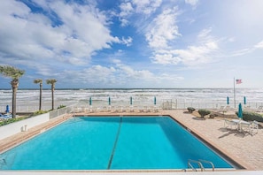A swimming pool with a view of the ocean, a flag, and lounge chairs. - 8D Royal Atlantic 2/2 ocean view unit. (Daytona Beach Shores)