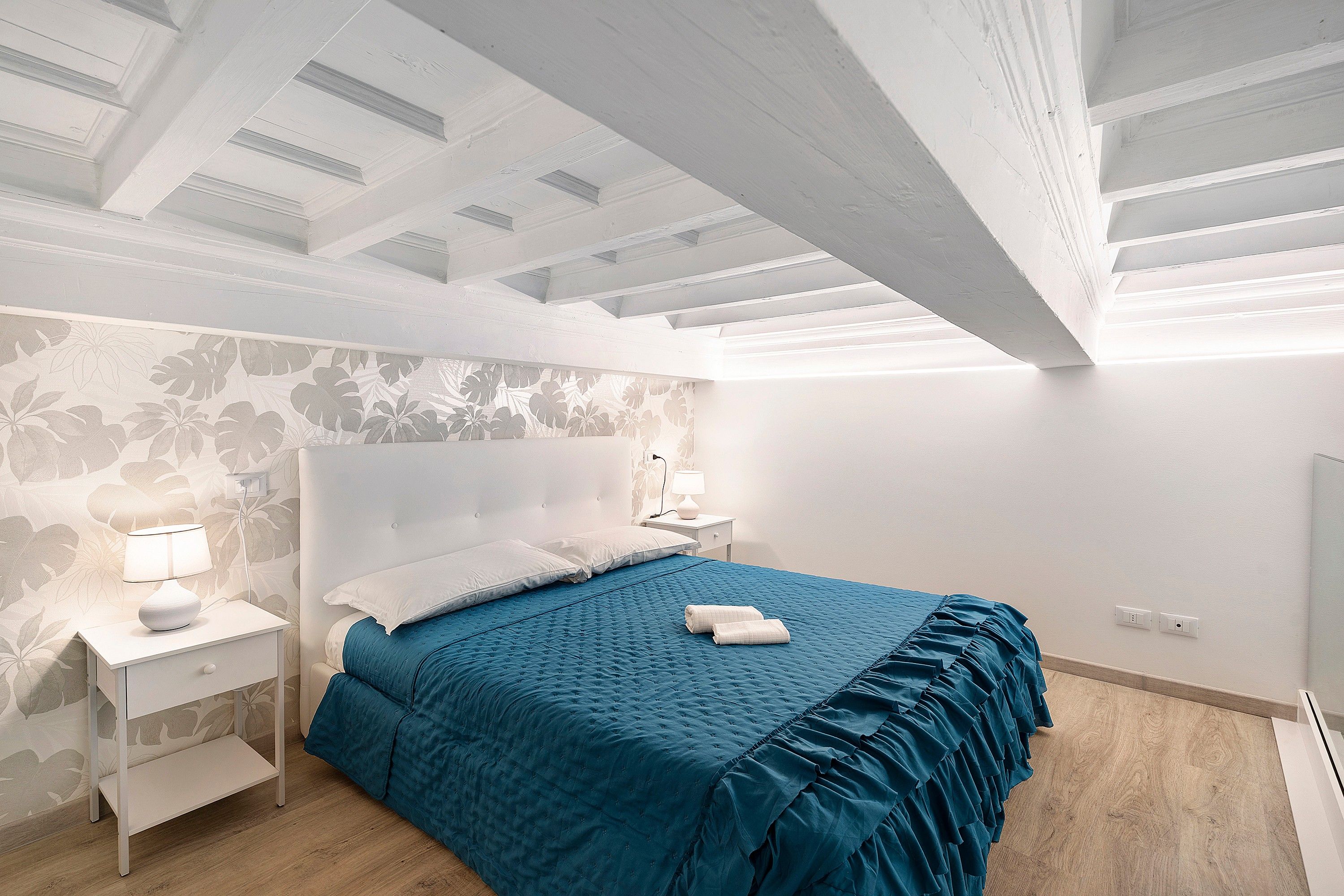 Una camera da letto moderna con un letto grande, un comodino, una lampada e una luce a parete.