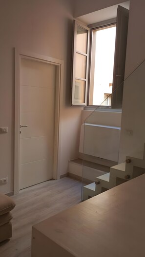 Ein Zimmer mit einer Tür, einem Fenster und einer Treppe.