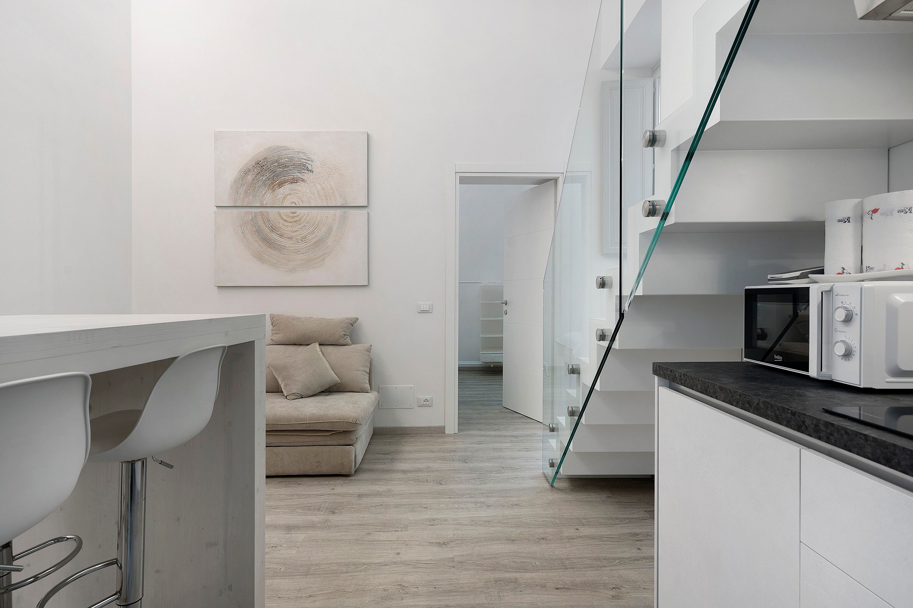 Eine moderne Küche mit Mikrowelle, einer Vitrine und einer Couch im Hintergrund.