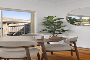 A dining area with a round table, four chairs, and two white cups. - Bright 1-Bed House Near Thornbury Cafes (Thornbury)