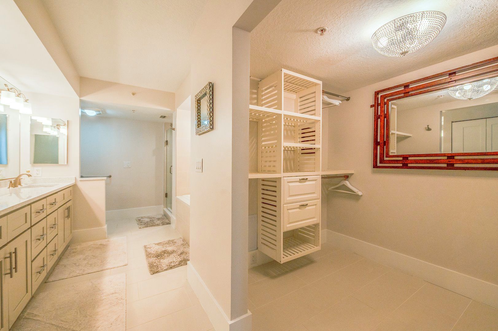 Une salle de bain avec une douche à l’italienne, un meuble-lavabo avec un miroir et un espace de rangement intégré.