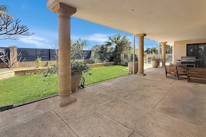 A covered patio area with stone flooring, columns, and a barbecue setup. - Beachside 4-Bed House With Pool In Warnbro (Warnbro)