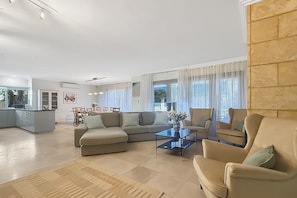 A spacious living room with a large sectional sofa, a coffee table, and a dining area with a long table and chairs. - Beachside 4-Bed House With Pool In Warnbro (Warnbro)