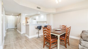 A modern kitchen with white cabinets, a central island, and bar stools. - A506 Links South in Ponce Inlet, FL (Ponce Inlet)
