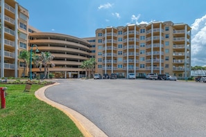 A multi-story parking garage with a curved entrance, surrounded by a grassy area and palm trees. - A506 Links South in Ponce Inlet, FL (Ponce Inlet)