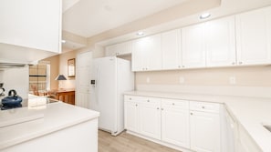 A modern kitchen with white cabinetry, a built-in oven, and a refrigerator. - A506 Links South in Ponce Inlet, FL (Ponce Inlet)