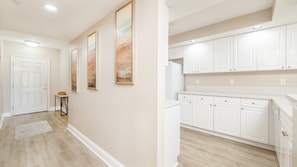 A hallway with a door, a small table, and three framed pictures on the wall. - A506 Links South in Ponce Inlet, FL (Ponce Inlet)