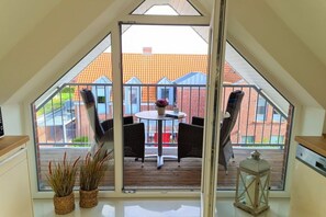 Een balkon met een tafel en stoelen, uitzicht op een gebouw van baksteen, en een lantaarn.