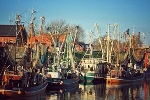 A harbor with multiple fishing boats docked, surrounded by buildings. - Holiday apartment with 2 bedrooms (Greetsiel)